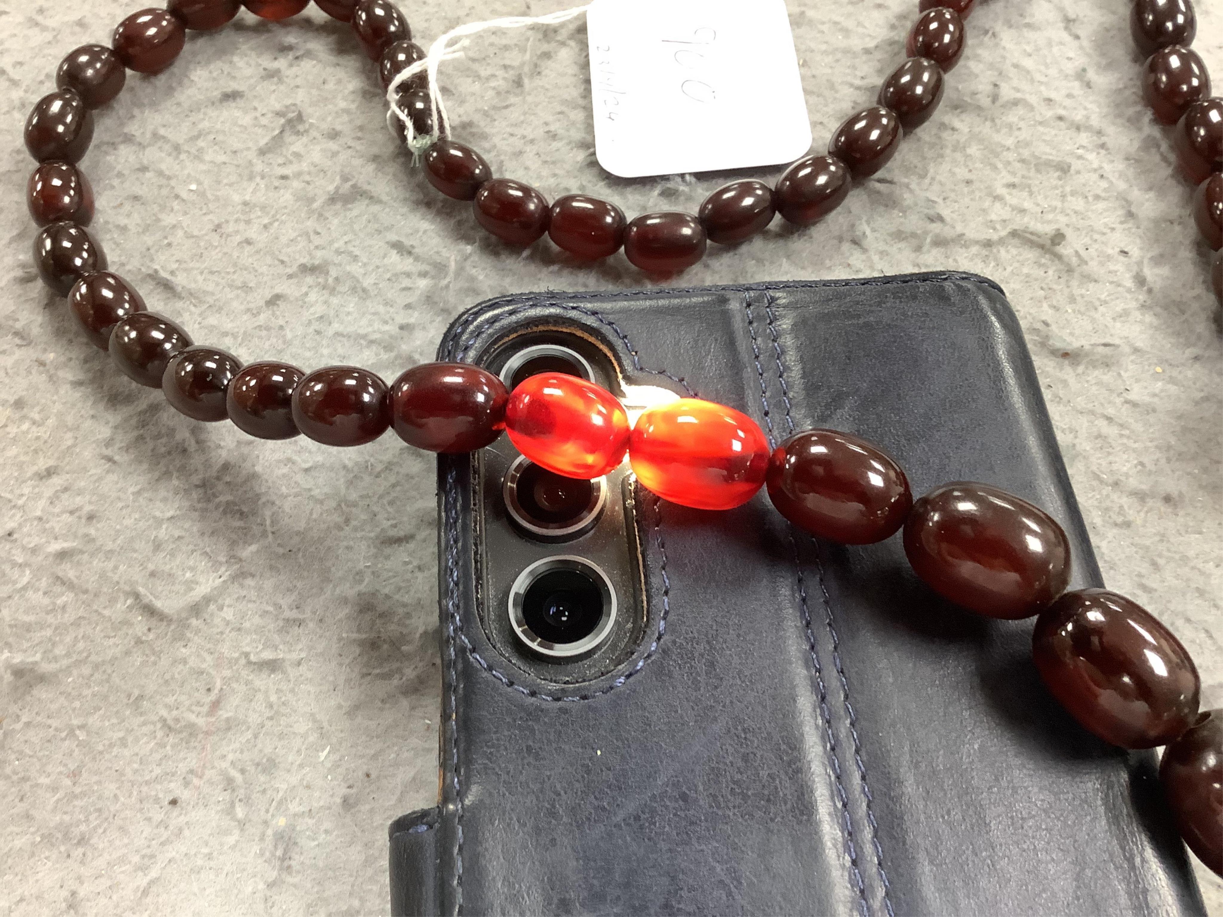 A single strand graduated simulated cherry amber oval bead necklace, 98cm, gross weight 140 grams. Condition - fair to good